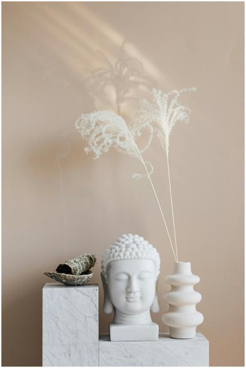 Bowl with sage candle placed on white marble stand
