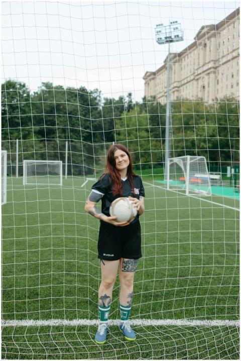 A woman soccer player standing with a ball on a gr