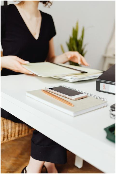 Faceless woman organizing documents at office desk