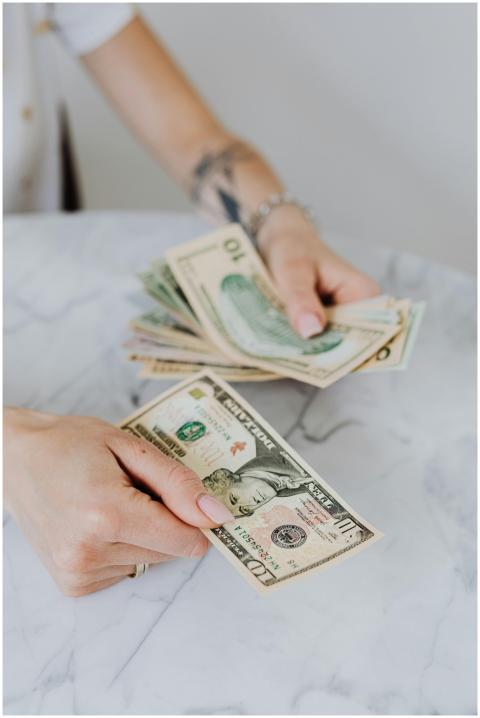 Close-up of hands counting US dollar bills on a ma