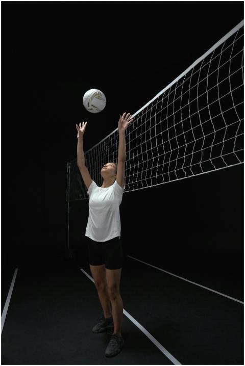 Athletic woman playing volleyball indoors, set aga