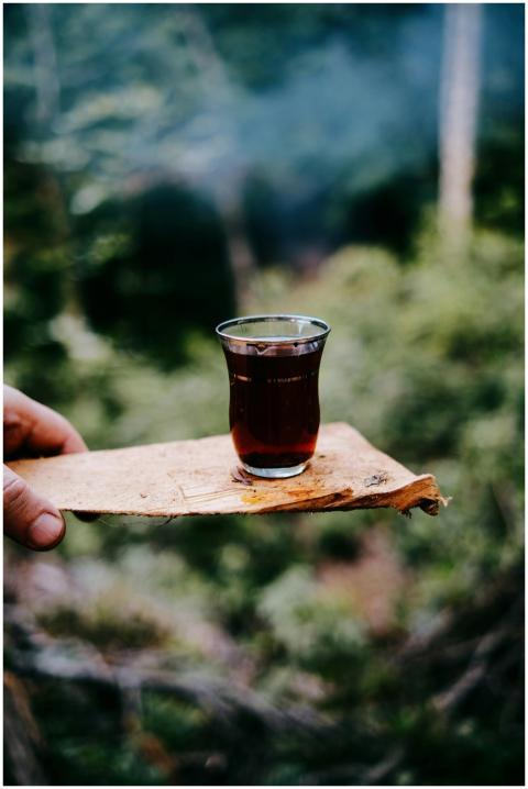 Glass of tea on a rustic wooden tray outdoors, evo