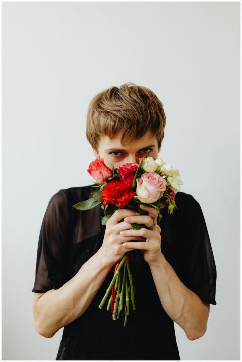 Person holding and smelling a vibrant bouquet of r