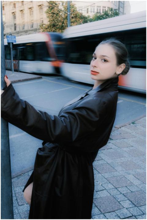 Portrait of a young woman in a dark trench coat st