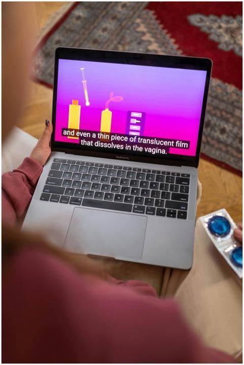 Person holding laptop with sex education video and