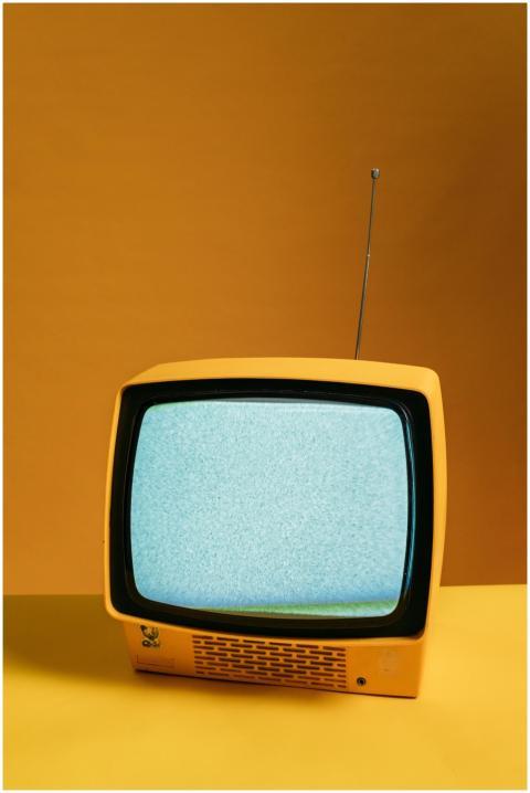Retro yellow television on orange backdrop with st