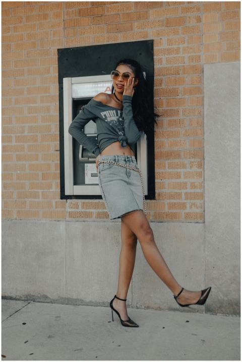 Trendy young woman with sunglasses poses by an ATM