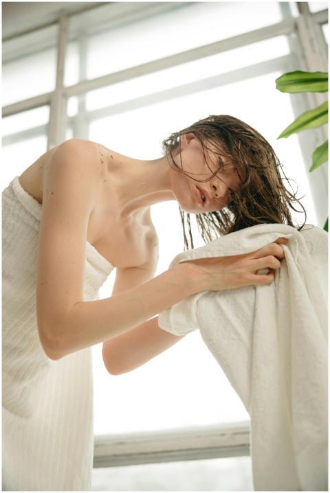 Side view of a woman drying her hair with a towel
