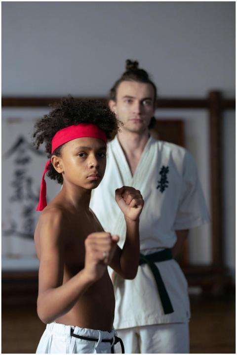A young boy practicing martial arts with his train