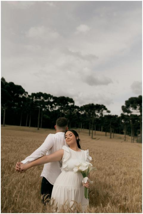 A couple in a wheat field embracing, woman in whit