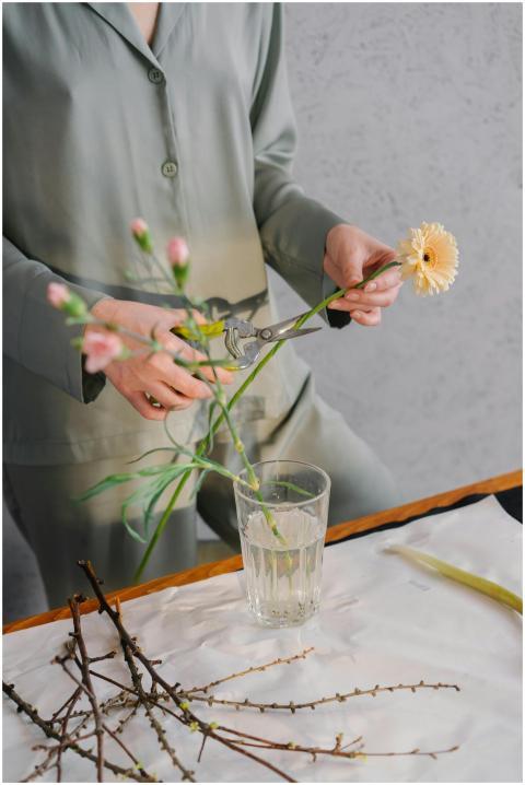 A woman in green outfit trimming flowers for a flo