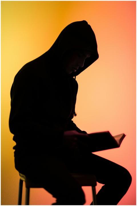 Silhouette of a man reading a book with a colorful
