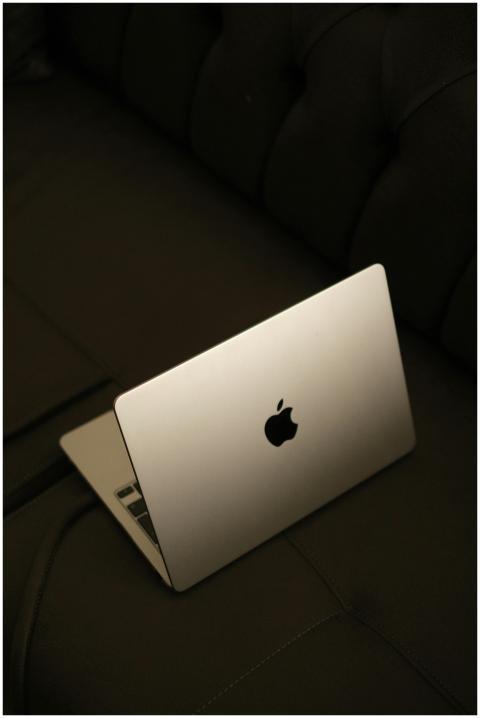 A minimalist shot of a sleek laptop on a dark sofa
