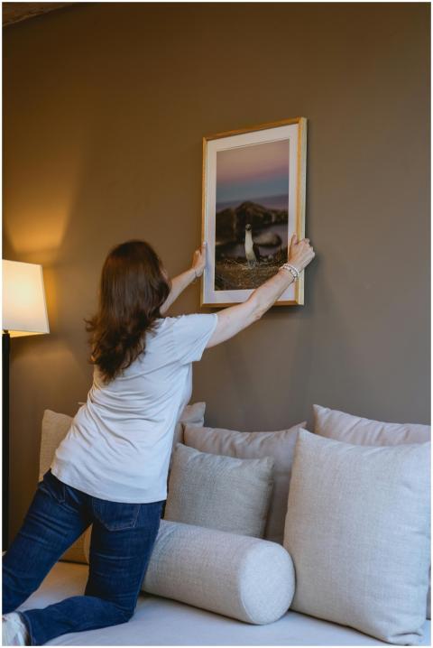 Woman adjusting framed art on a wall with cozy dec