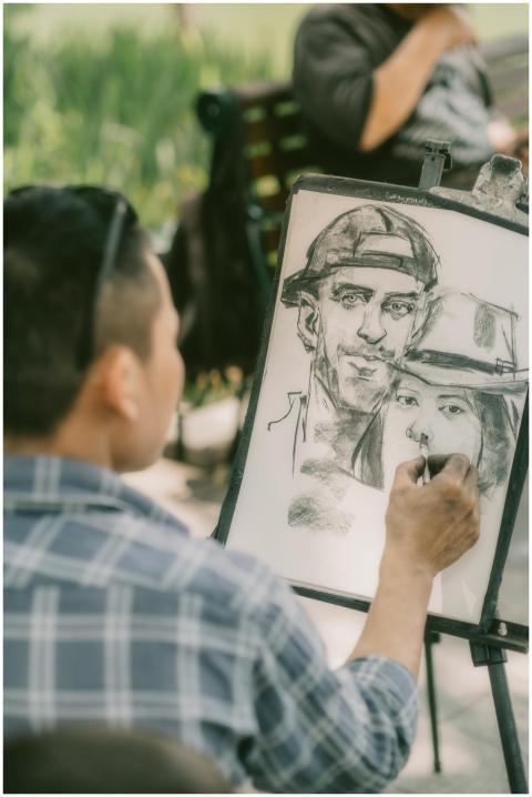 Man sketching portraits on easel in a park, captur