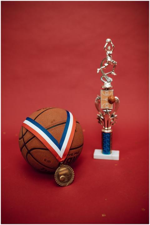 Basketball with gold medal and trophy on a red bac
