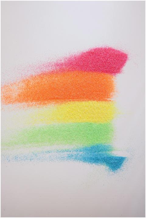 Colorful rainbow powder arranged in stripes on a w