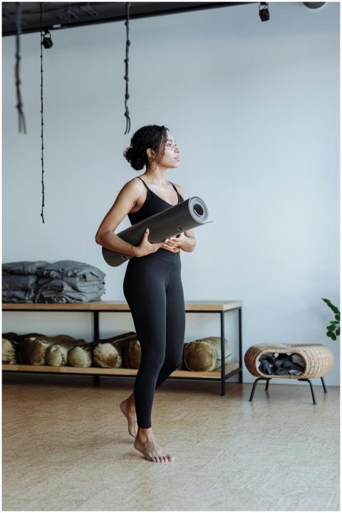Black woman standing in a yoga studio holding a yo