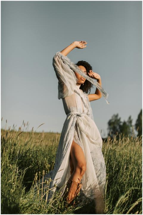 A woman poses gracefully in a sheer, flowing dress