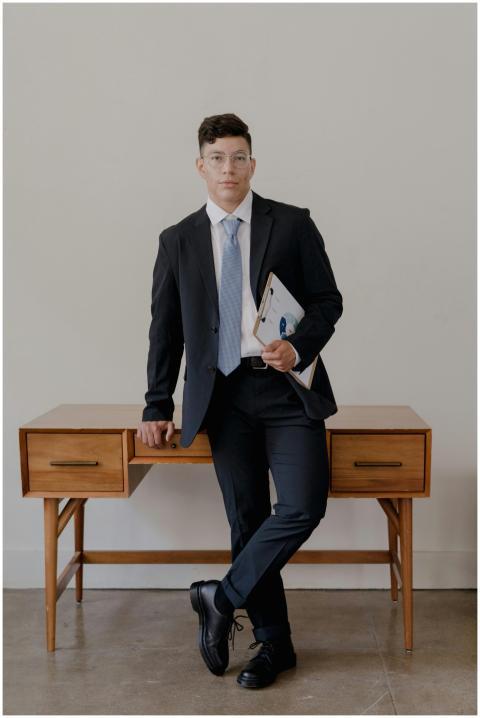 Confident businessman in a black suit leaning on a