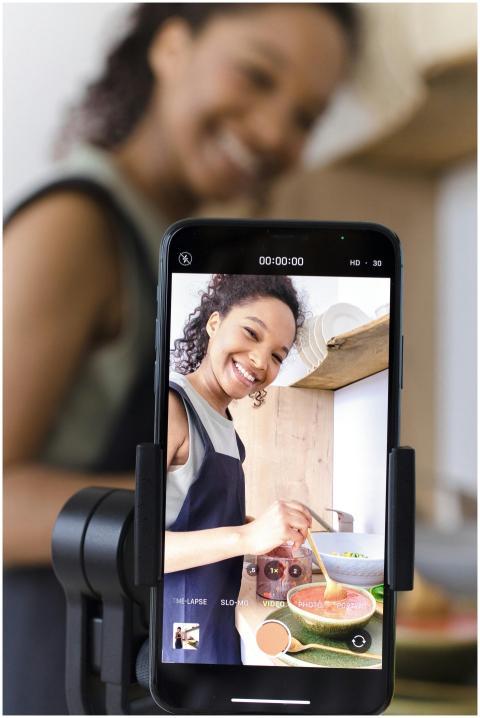 Smiling woman filming cooking video on smartphone