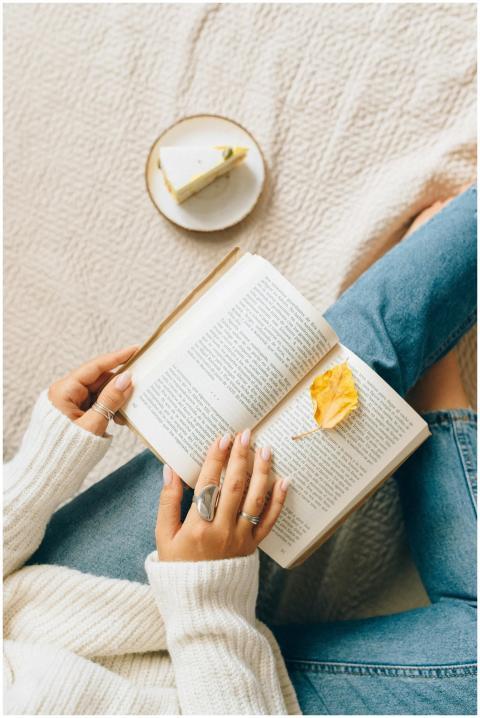A woman enjoys a book with cake and a cozy atmosph