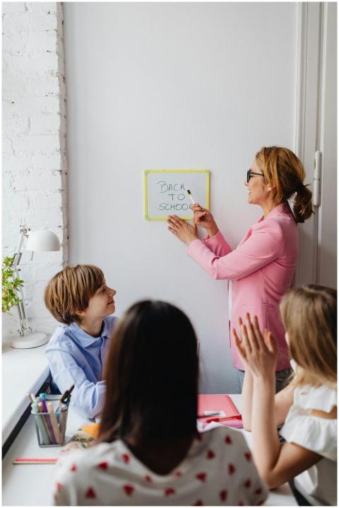 A teacher in a pink blazer interacts with students