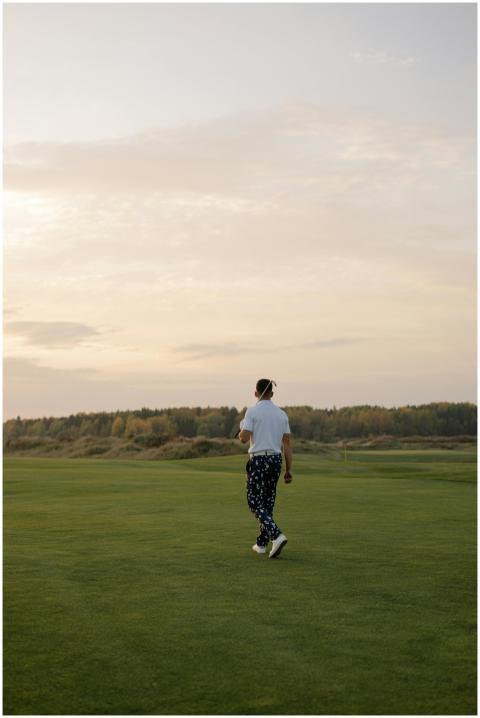 A golfer stylishly dressed stands on a golf course