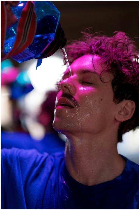 Sweaty man pouring water on his face under vibrant