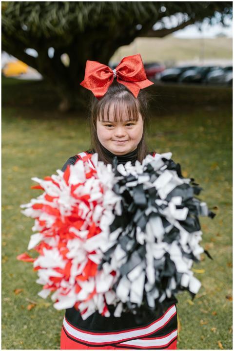 Portrait of a smiling cheerleader holding red and