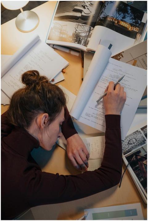 A woman sleeping on a desk surrounded by papers, i