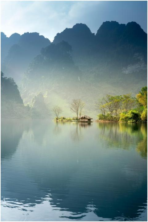 Scenic view of a foggy lake surrounded by lush mou