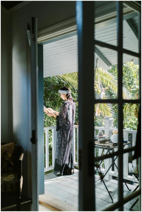 Woman in black dress reading on a sunny balcony th