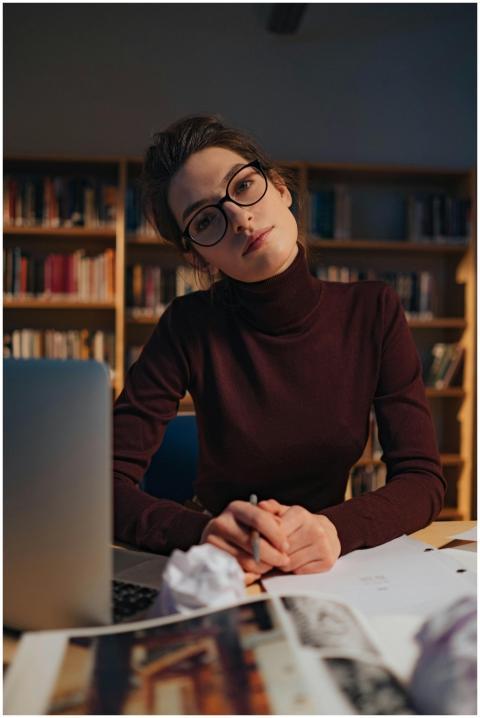 A woman in glasses studies intently at a library w