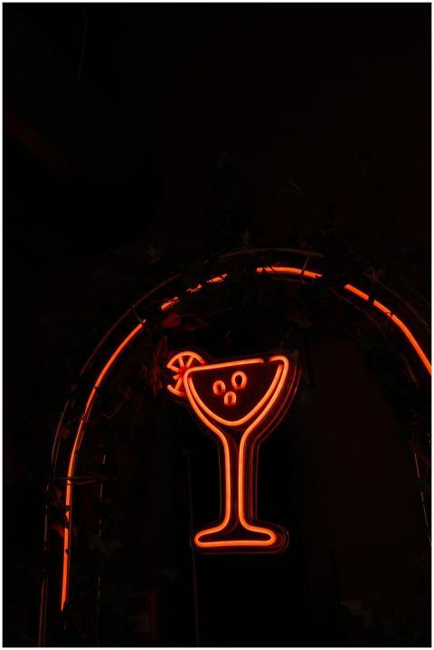 Vibrant neon cocktail sign glowing in a dark backg
