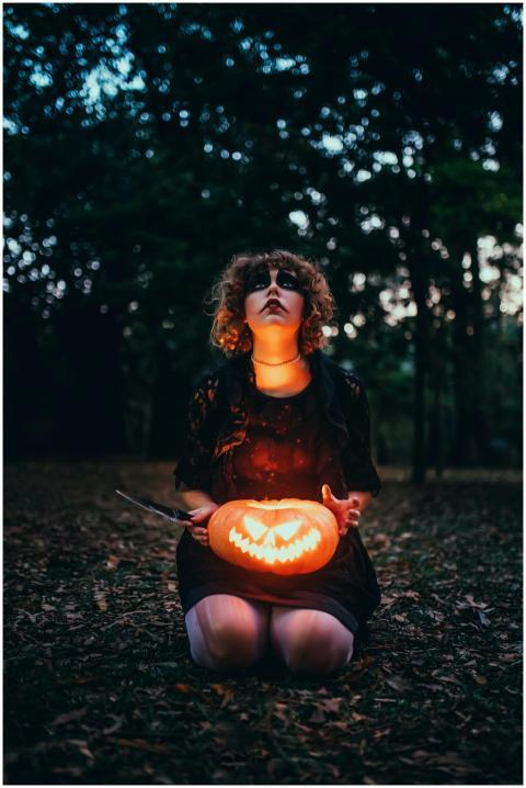 A mysterious woman kneels in a dark park with a gl