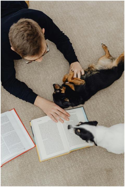 Teen reading a book on the floor, surrounded by pl