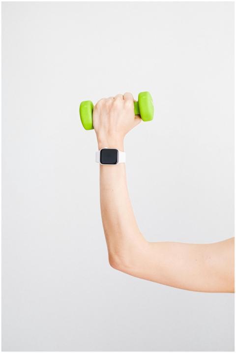 Arm holding a green dumbbell with a smartwatch on