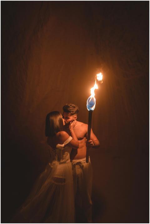 A couple shares a romantic kiss illuminated by tor