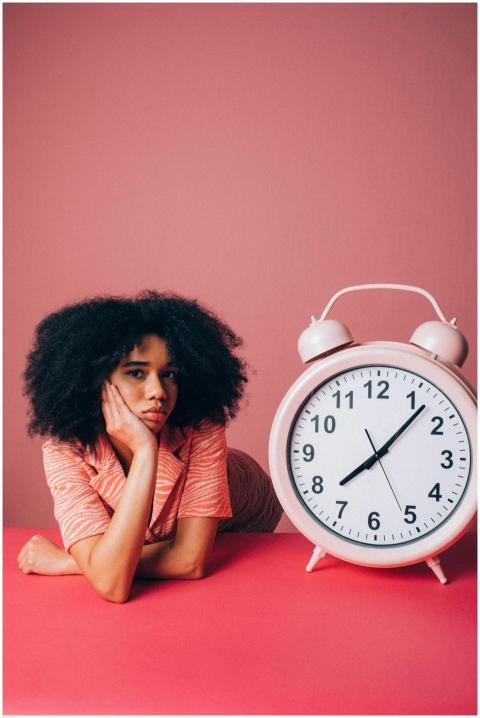 Woman with afro hair leaning on table beside large