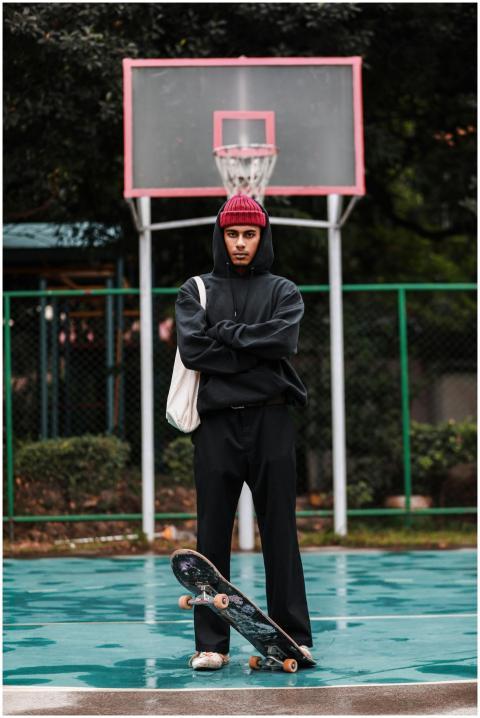 Stylish young man stands confidently with skateboa