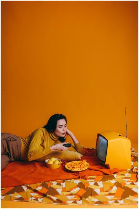 Woman in yellow outfit watching vintage TV with sn