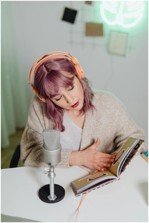 A young woman with purple hair reads a book while