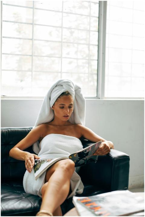 Caucasian woman in towel reading a magazine on a c