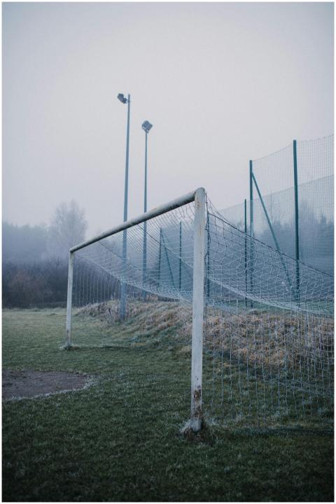 Misty soccer field featuring a weathered goalpost