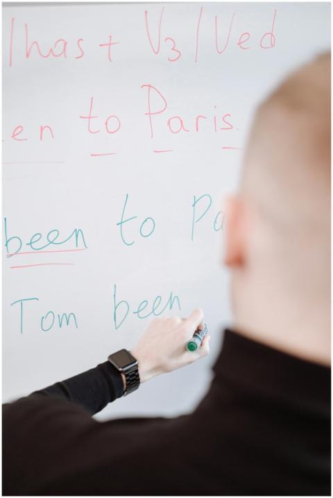 A person writing grammar instructions on a whitebo
