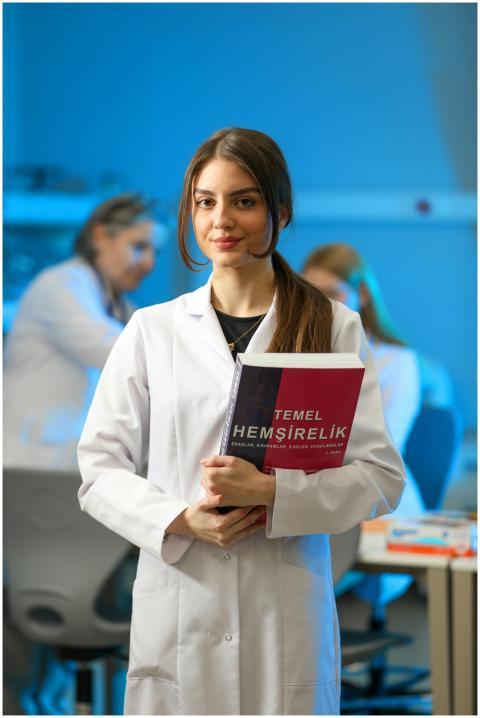 Young woman in a lab coat holding a nursing textbo