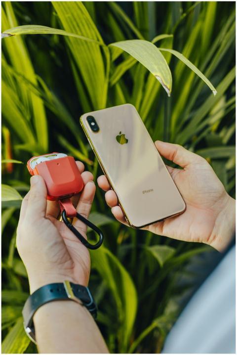 Close-up of hands holding a smartphone and a red g
