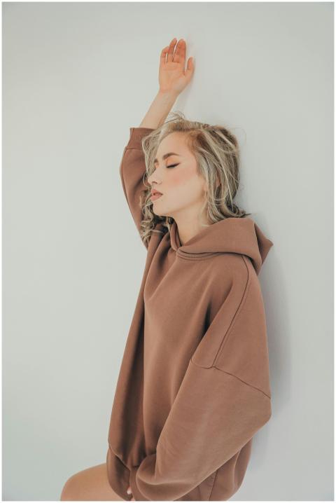 Stylish and serene young woman poses in brown hood