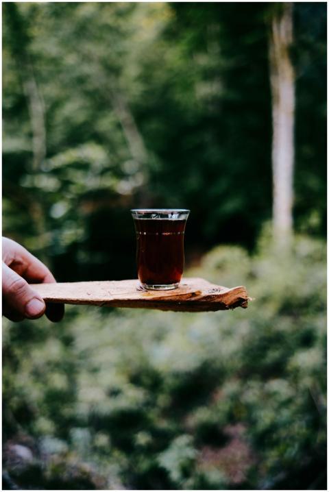 Glass of tea on a wooden tray held outdoors with f